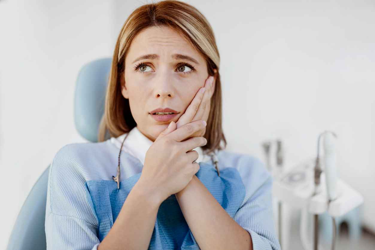 Woman complaining on toothache at the dentist. Symptoms of gums pain and Periodontal Disease